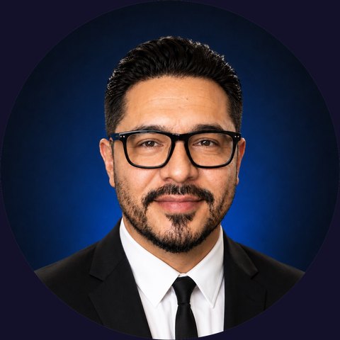 Headshot of Doc Alvarez, President of DocApply Mortgage Brokerage, wearing glasses and a dark suit against a blue studio backdrop